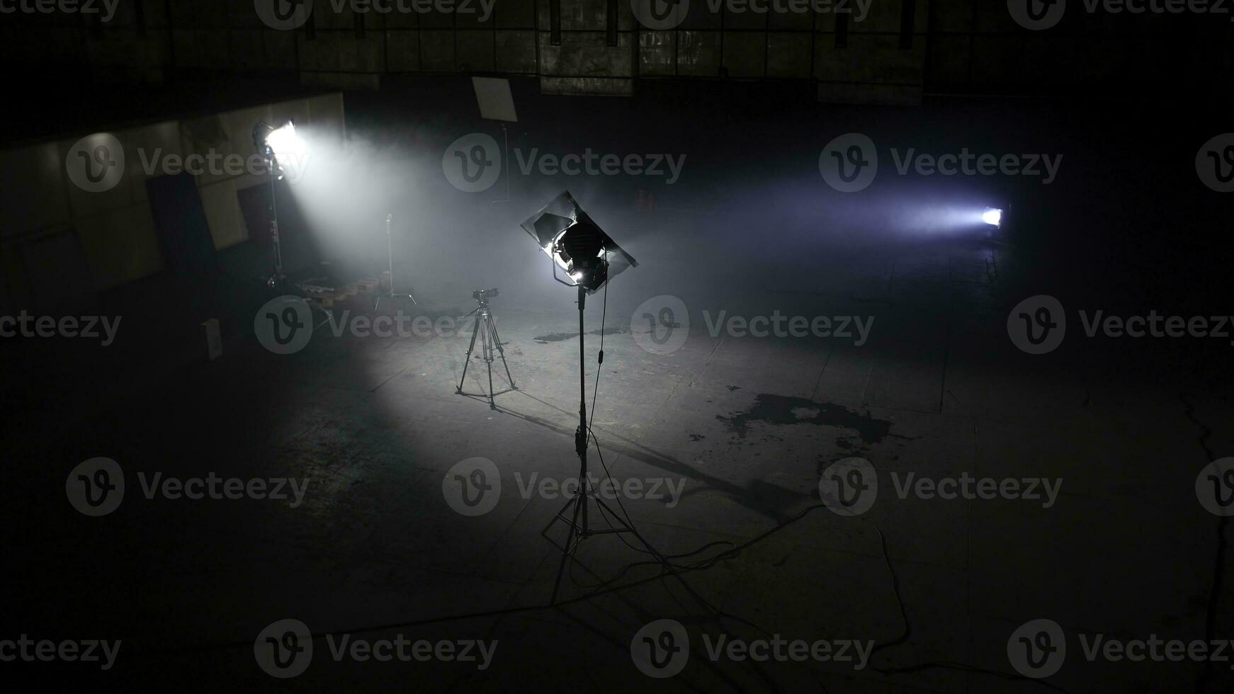 Dark photo studio with light spotlights. Spacious dark room with supplied floodlights and camera on tripod ready for professional shooting