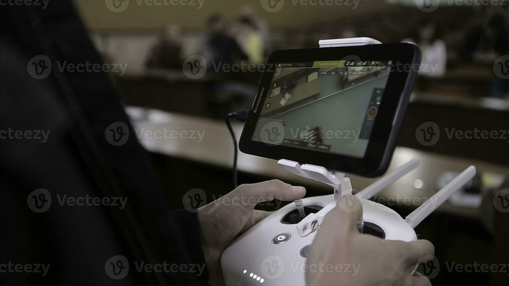Close-up of man's hands with a remote control flying a small quadcopter toy indoors photo