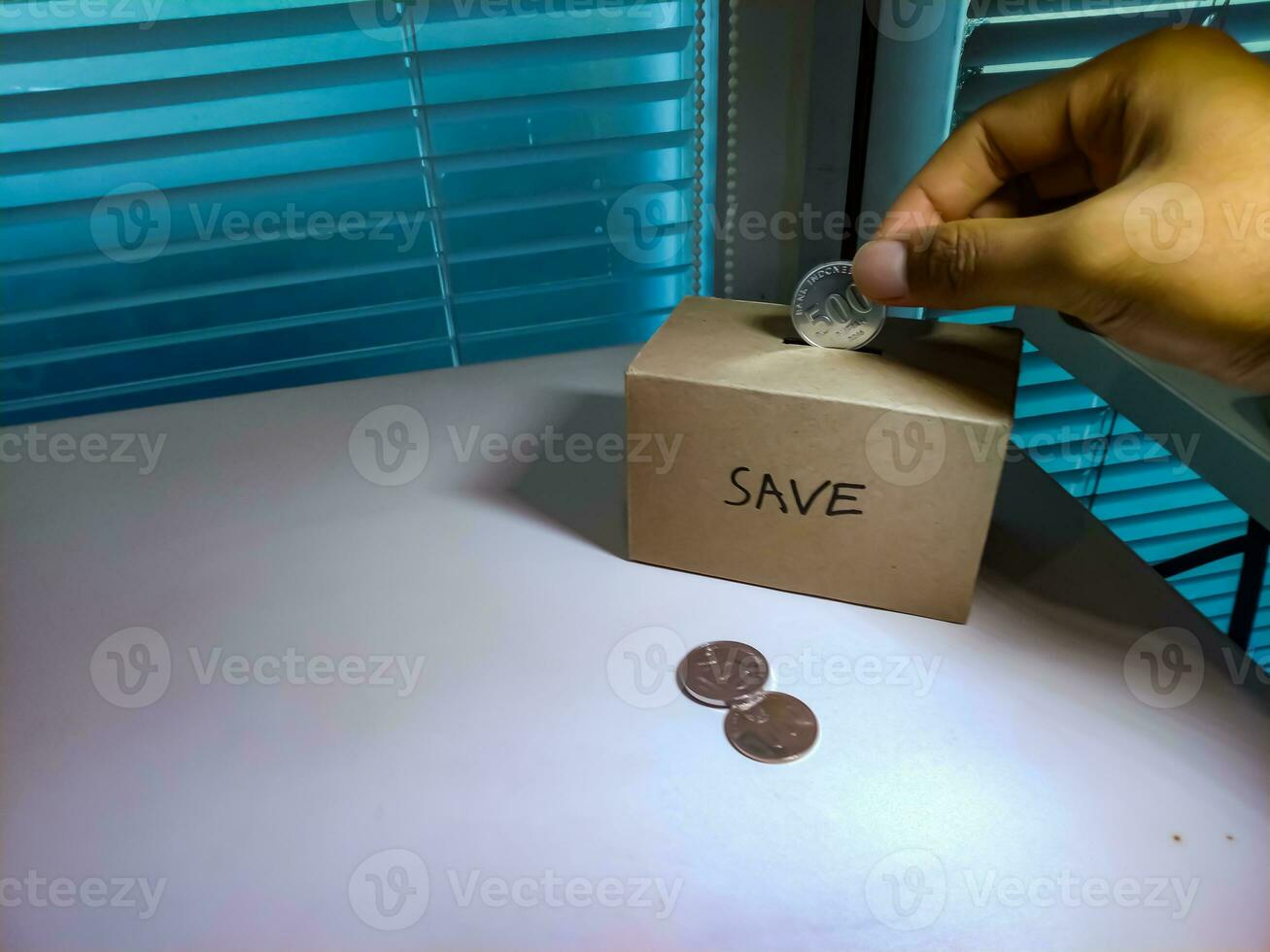 Saving money with hand putting coins in a box savings photo