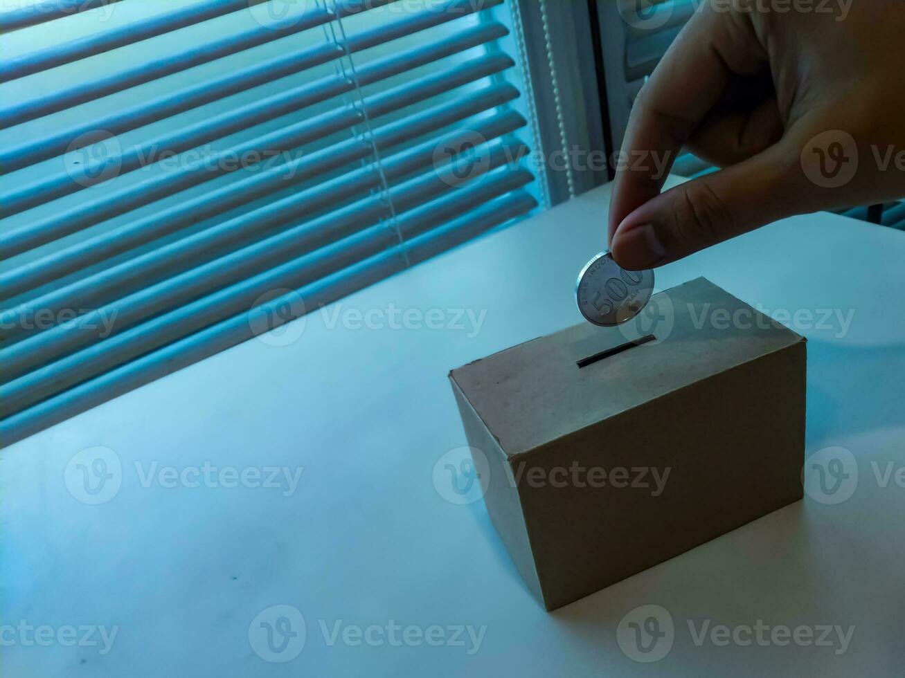 Saving money with hand putting coins in a box savings photo