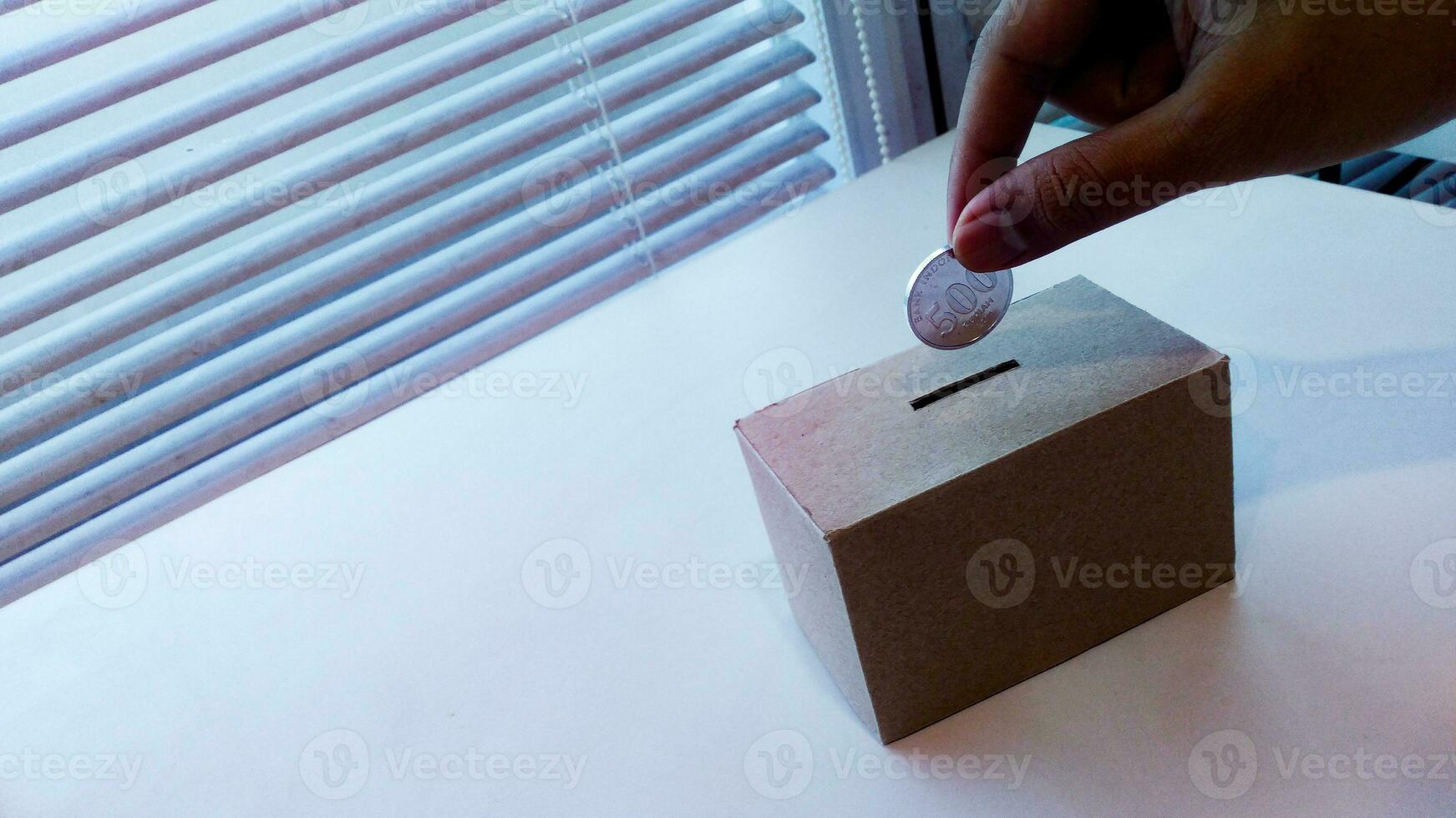 Saving money with hand putting coins in a box savings photo