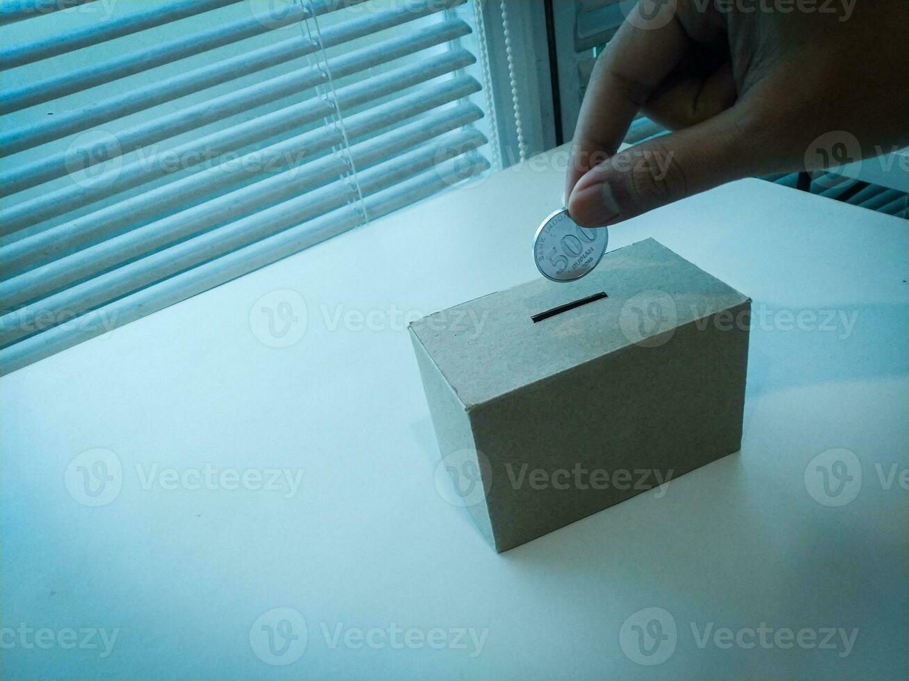 Saving money with hand putting coins in a box savings photo