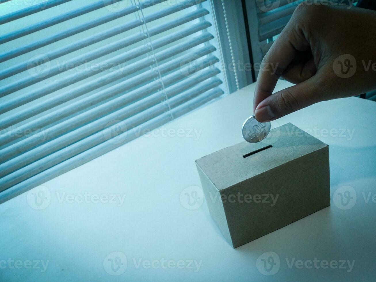 ahorro dinero con mano poniendo monedas en un caja ahorros foto