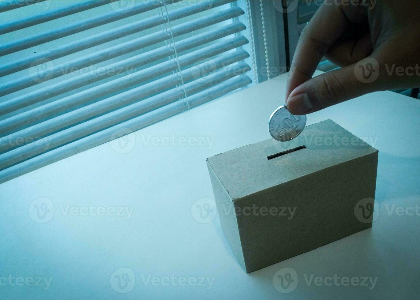 ahorro dinero con mano poniendo monedas en un caja ahorros foto