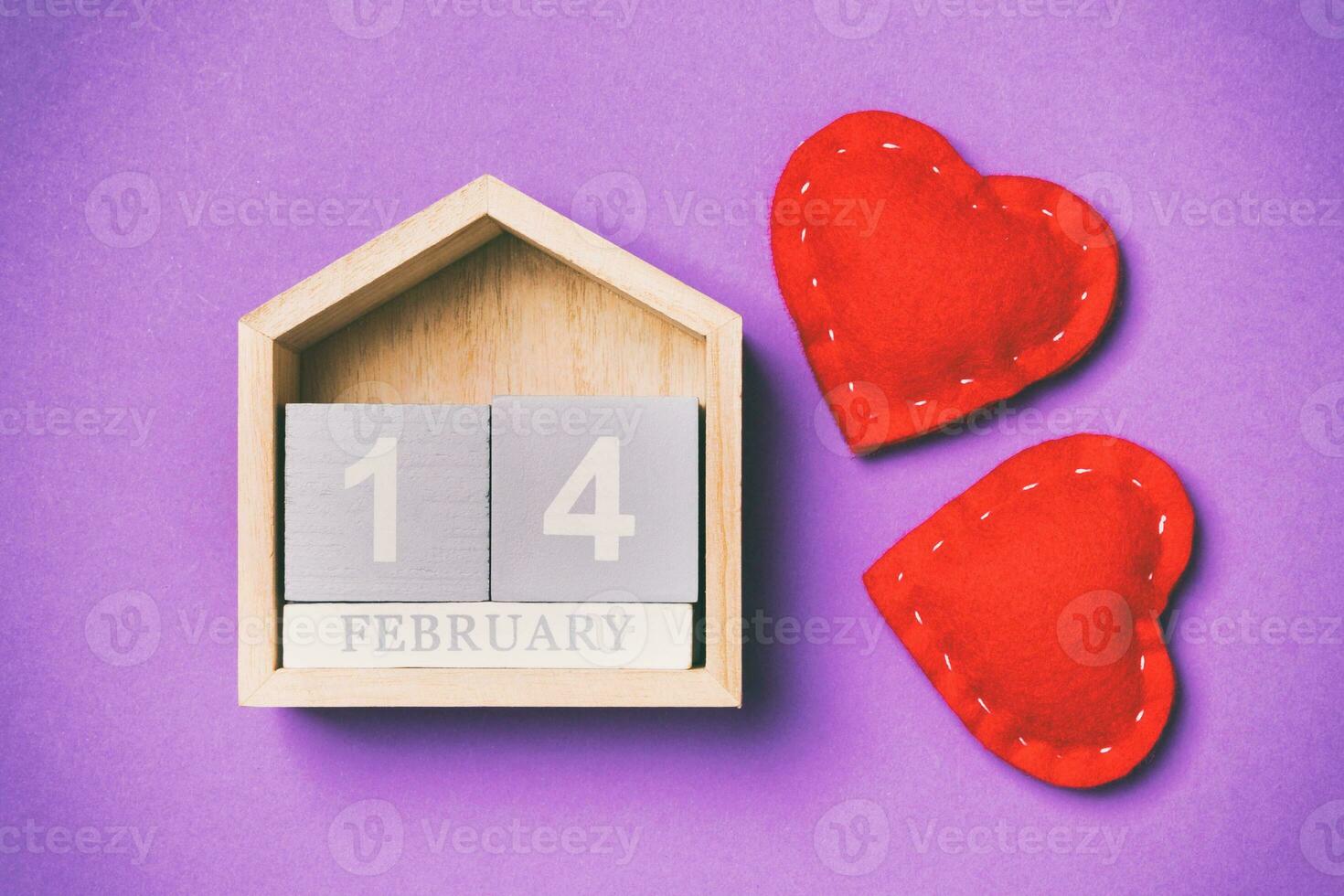Top view of wooden calendar and textile hearts on colorful background. The fourteenth of February. Valentine's day concept photo