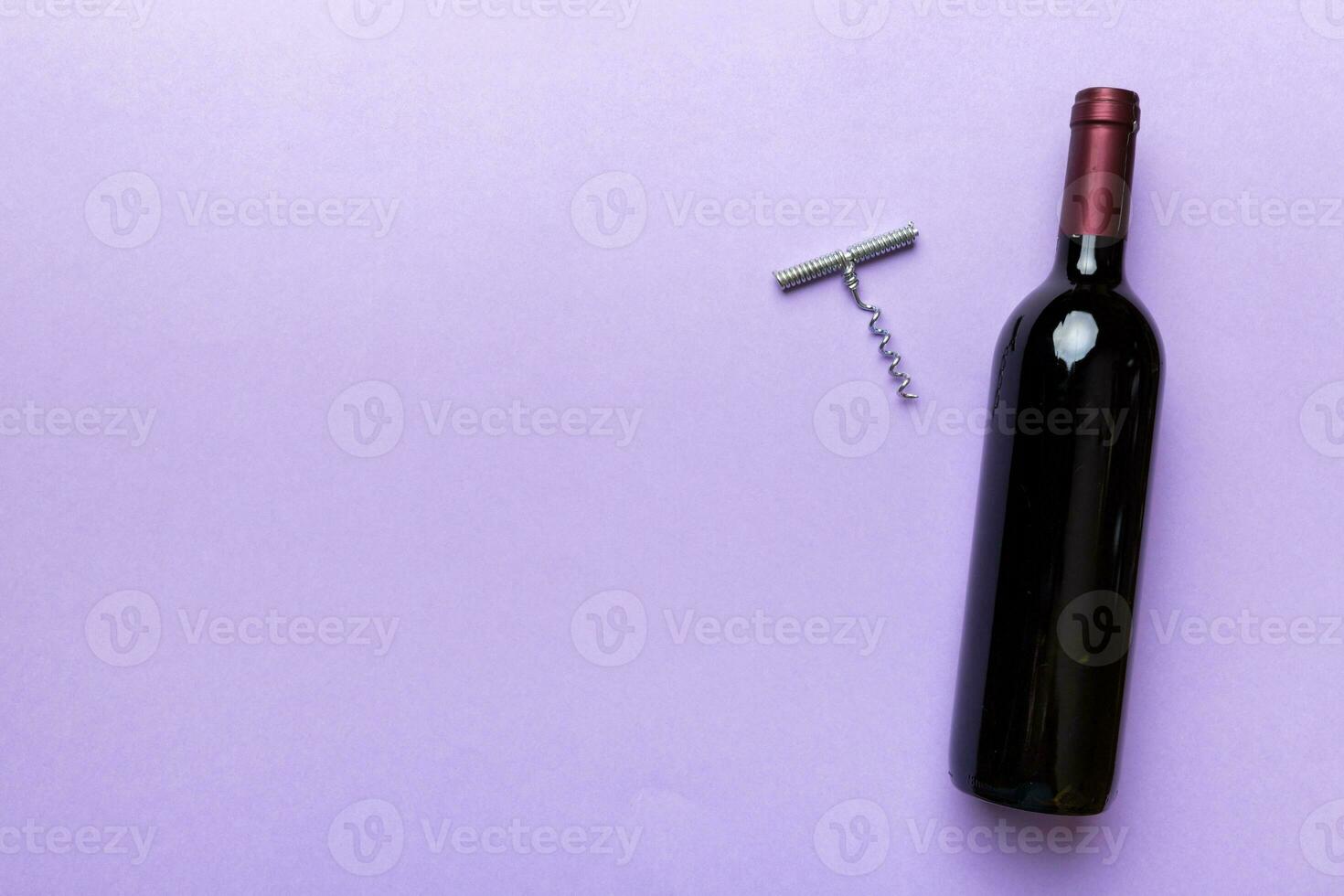 One Bottle of red wine with corkscrew on colored table. Flat lay, top view wth copy space photo