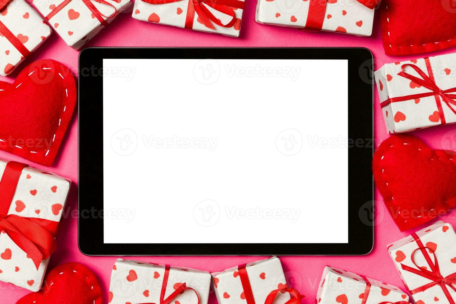 Top view of digital tablet surrounded with gift boxes and hearts on colorful background. Saint Valentine's day photo