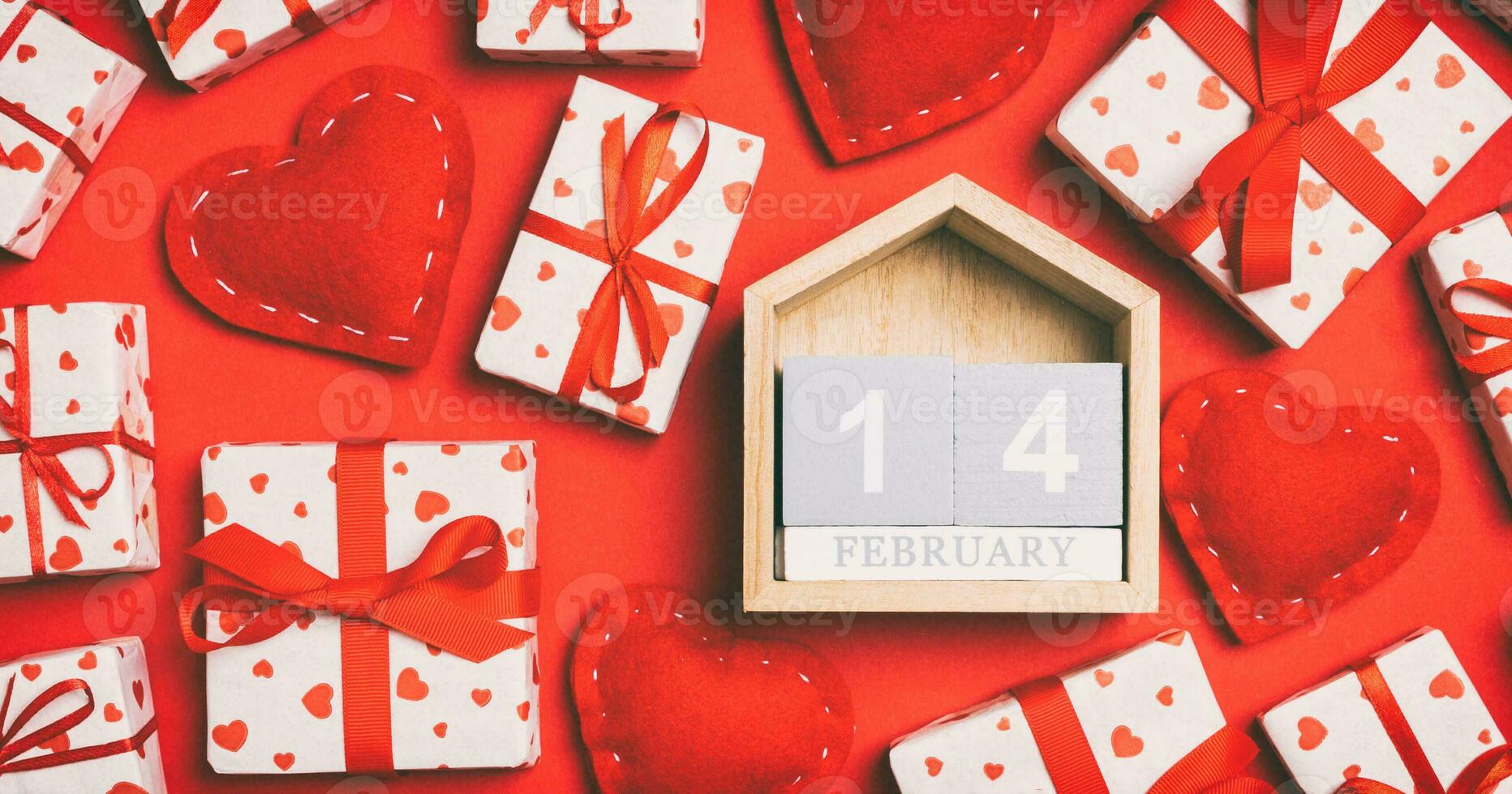 Top view of wooden calendar, white gift boxes and red textile hearts on colorful background. Valentine's Day concept photo