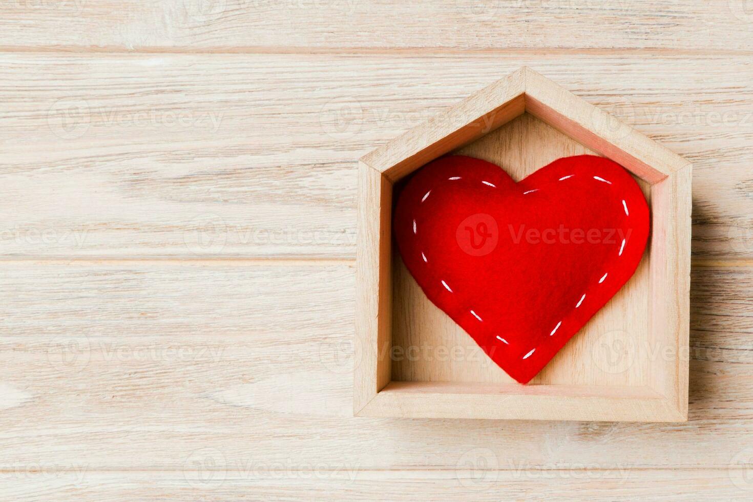 vista superior del corazón textil rojo en una casa sobre fondo de madera. concepto de hogar dulce hogar. día de San Valentín foto