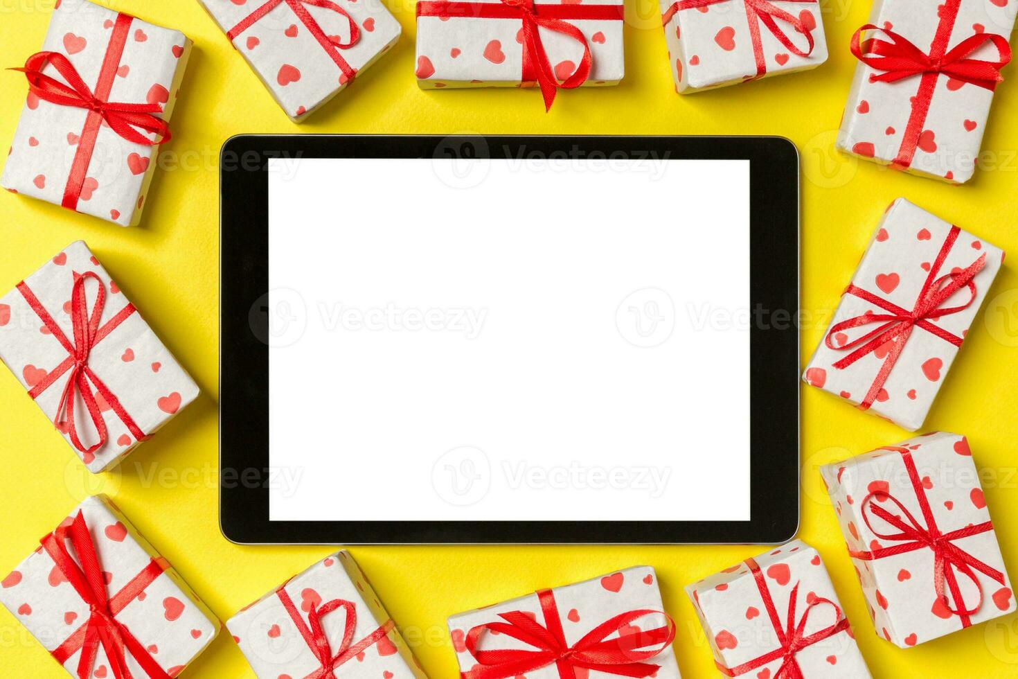 Top view of digital tablet surrounded with gift boxes on colorful background. Saint Valentine's day photo