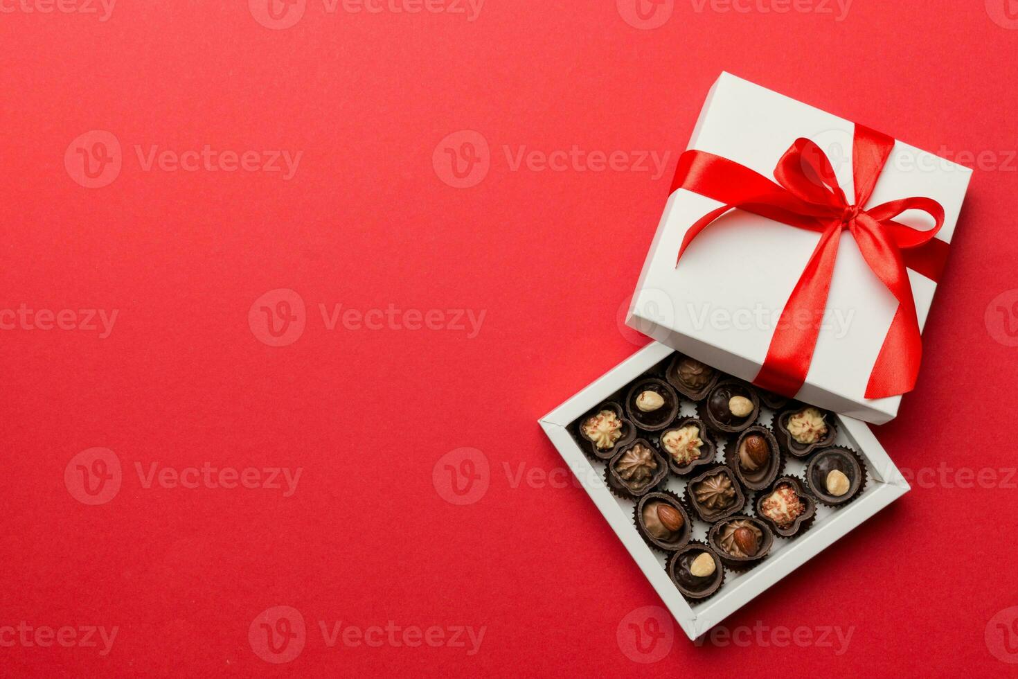 Delicious chocolate pralines in red box for Valentine's Day. Heart shaped box of chocolates top view with copy space photo