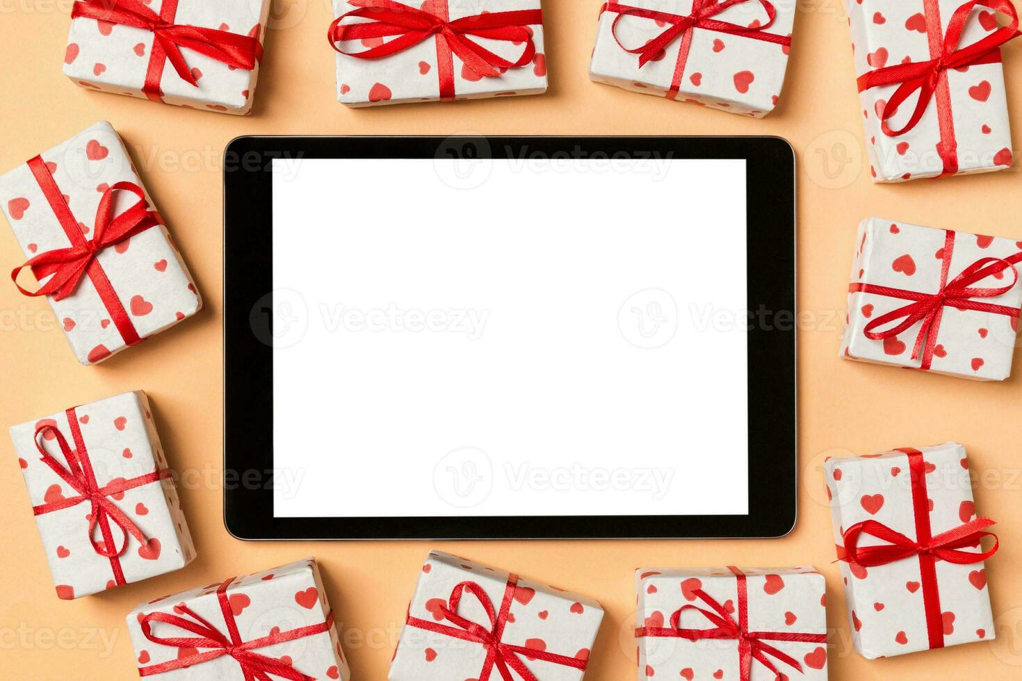 Top view of digital tablet surrounded with gift boxes on colorful background. Saint Valentine's day photo