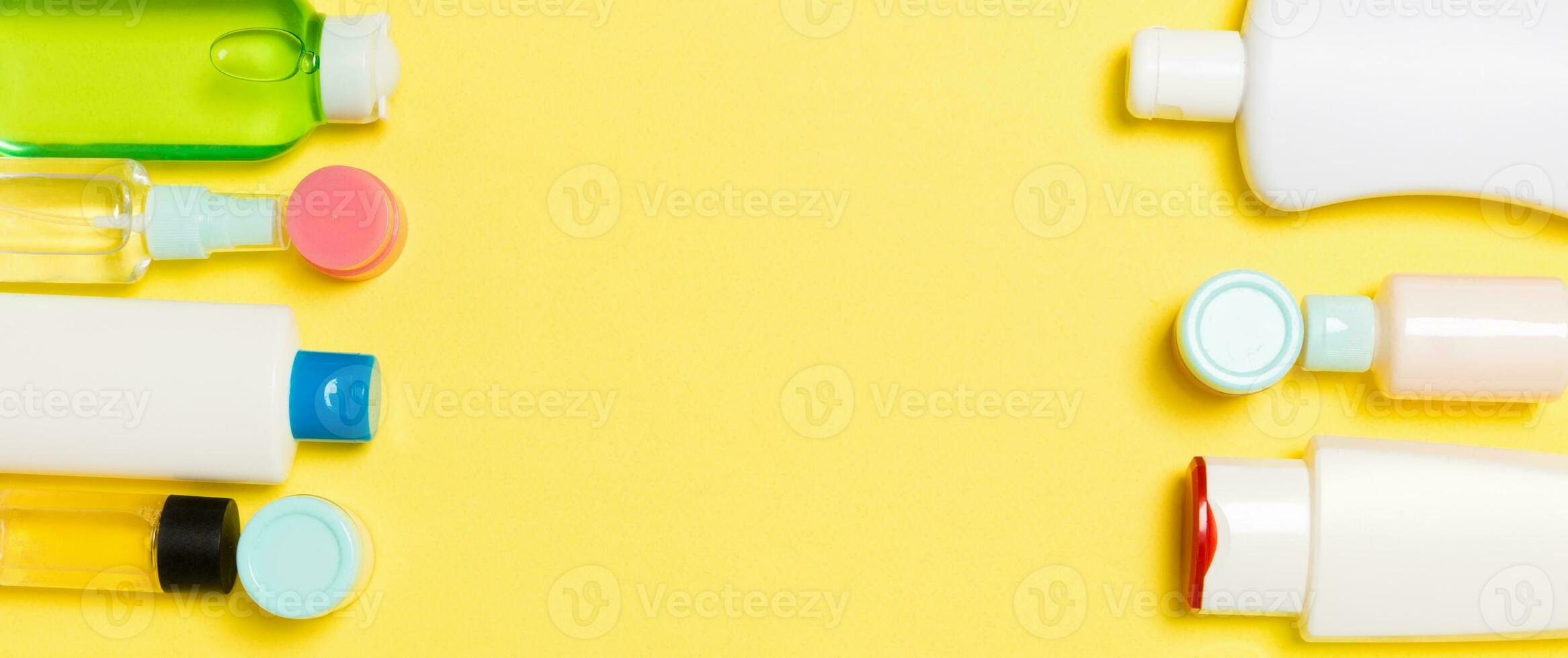 Composition of different sized cosmetic jars and bottles on yellow background. Beauty care concept with copy space photo