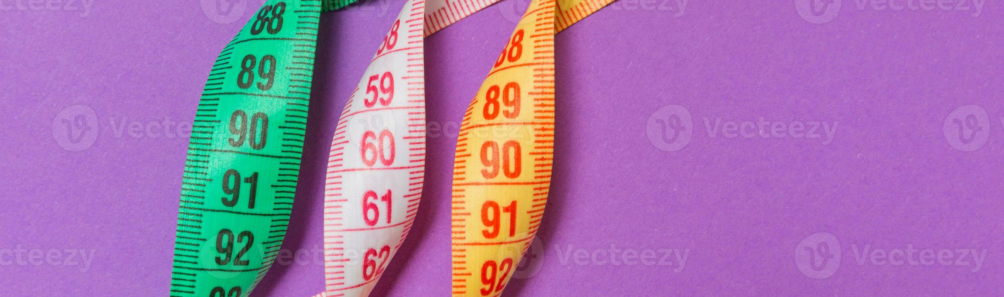 Perspective view of spiral colorful measure tapes on purple background. Concept of perfect female figure with empty space for your idea photo