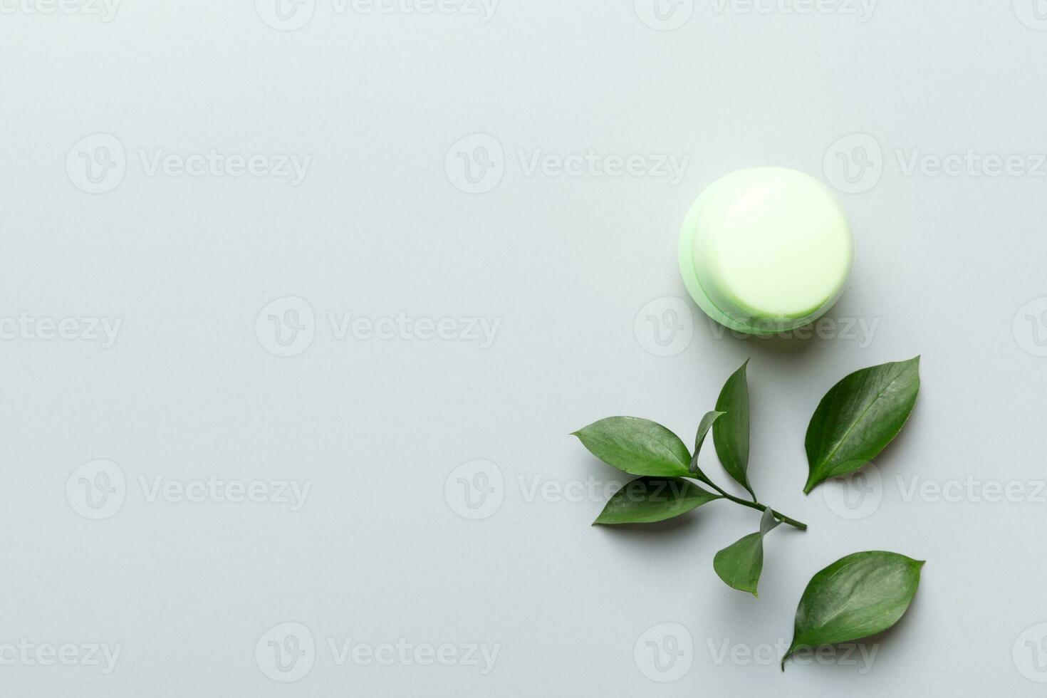 Organic cosmetic product with green leaves on color background. Copy space, flat lay photo