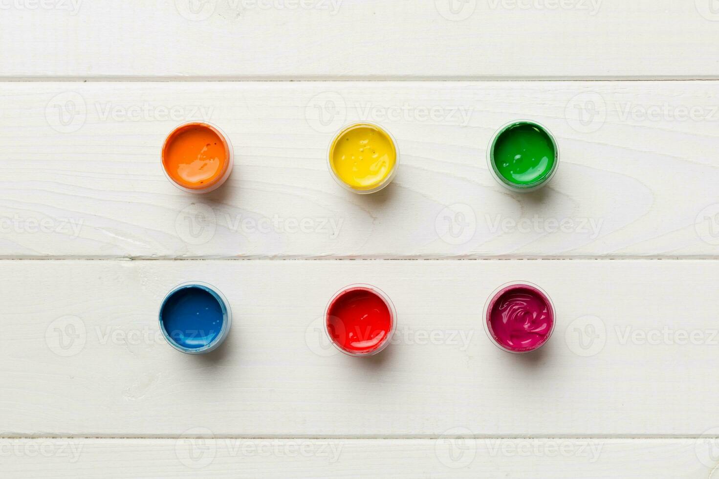 jars with gouache of different colors on Colored background. hobby painting. Top view with empty space. workplace for creativity. home teaching concept drawing photo