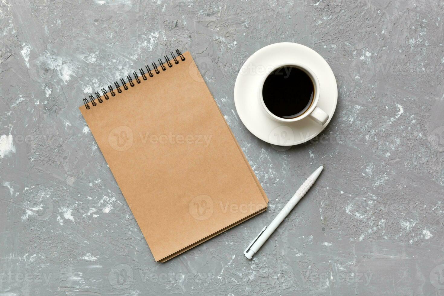 Modern office desk table with notebook and other supplies with cup of coffee. Blank notebook page for you design. Top view, flat lay photo