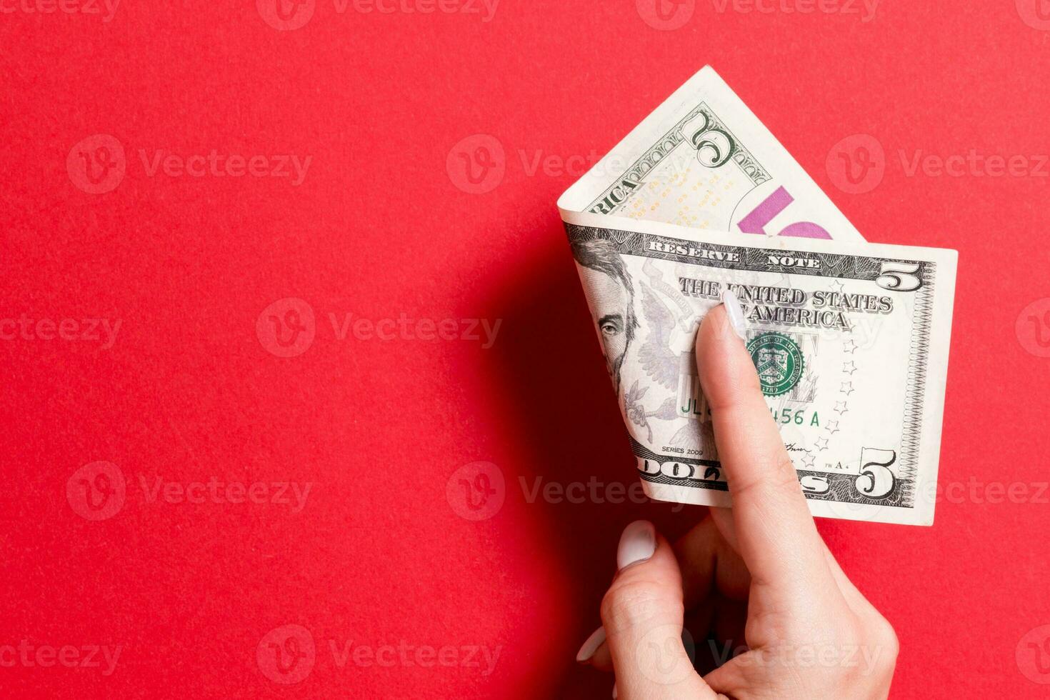 Top view of female hand holding a pack of money on colorful background. Five dollars. Business concept with empty space for your design. Charity and tips concept photo
