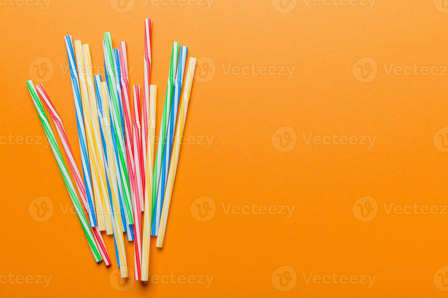 Heap of colorful plastic drinking straws on Colored background, flat lay. Copy Space for text photo