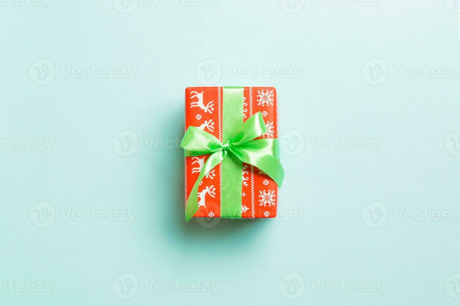 Gift box with green bow for Christmas or New Year day on blue background, top view with copy space photo