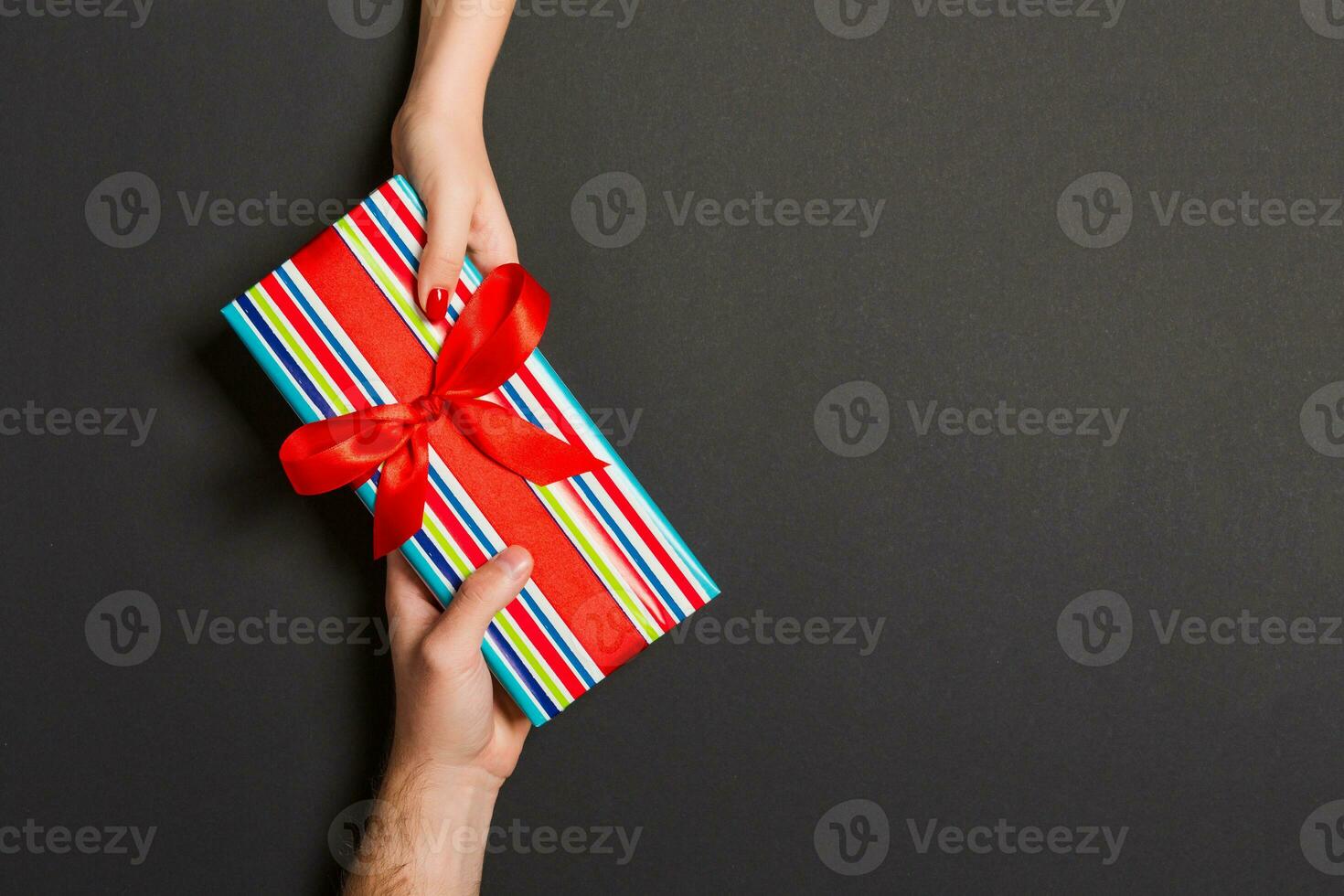Top view of giving a present to a lovely person on colorful background. Couple congratulate each other. Festive concept. Copy space photo