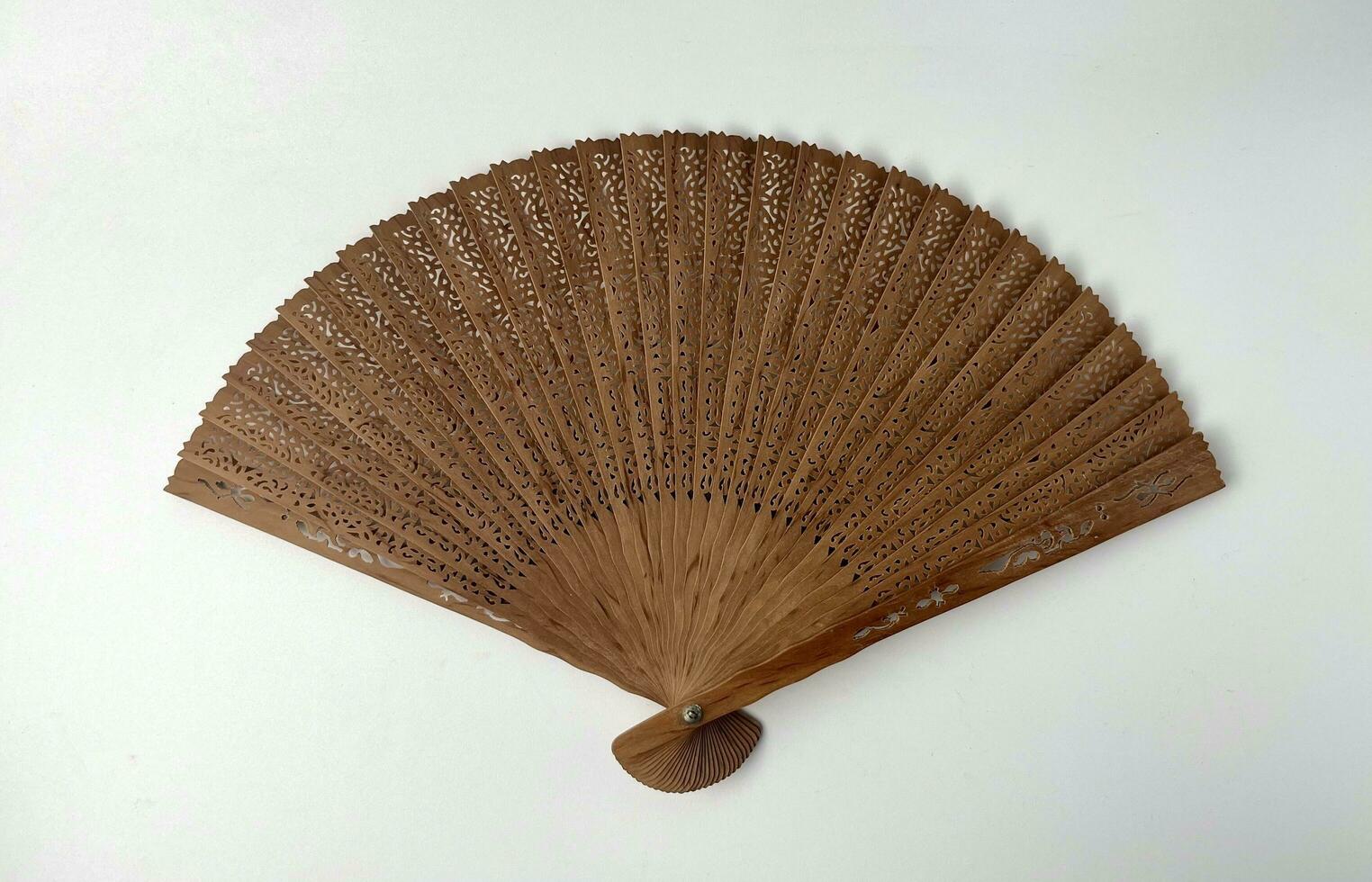 Opened hand held fan with wooden sandalwood material and beautiful carvings pattern decoration isolated on plain horizontal background. photo