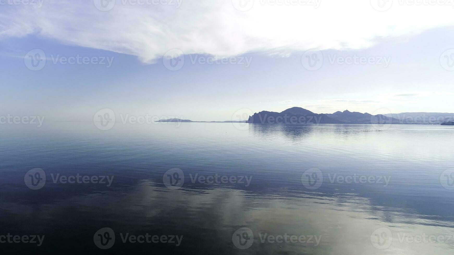 Beautiful sunrise and the morning haze hanging above the lake. Shot. Amazing blue sky and calm water, fog, and silhouettes of hills. photo