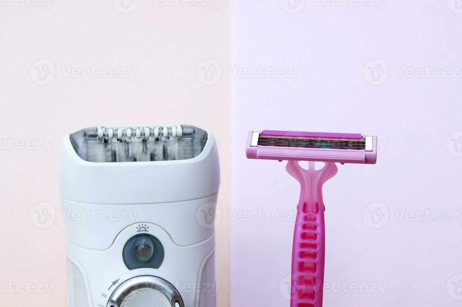 White epilator and pink razor on a pink background. photo
