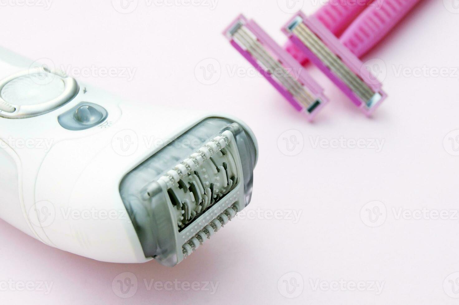 White epilator and pink razor on a pink background. photo