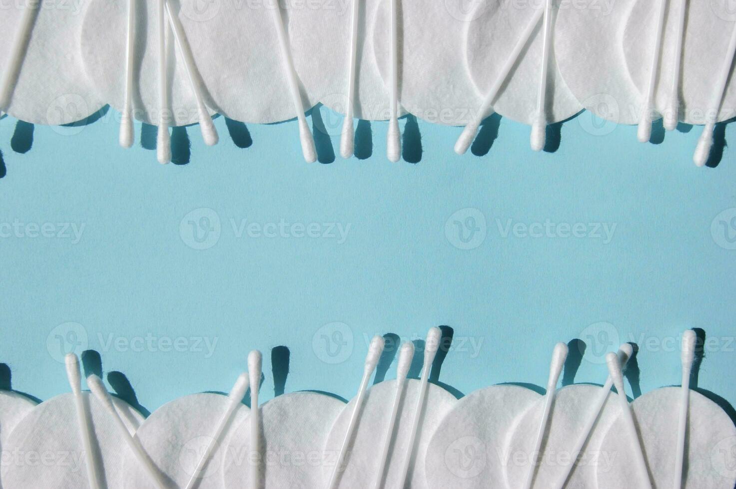 Ear sticks, white cotton pads on a blue background with copy space. photo