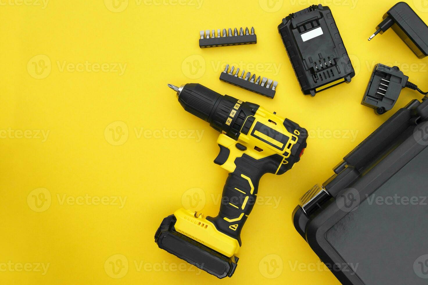The yellow-black screwdriver on a yellow background, a set of bits. photo