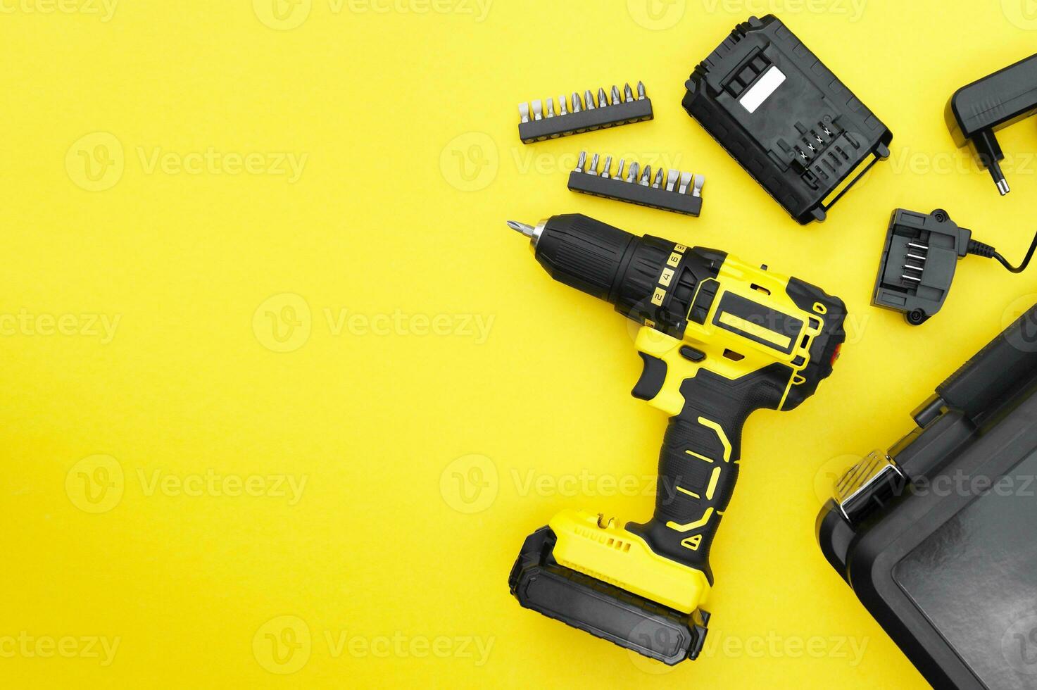 The yellow-black screwdriver on a yellow background, a set of bits. photo