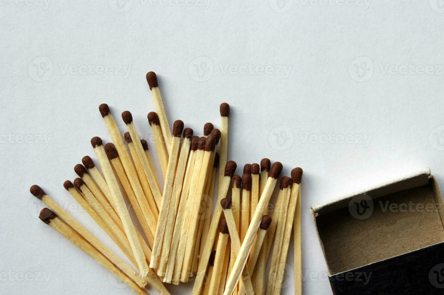 Wooden protective matches are scattered around a cardboard matchbox. photo