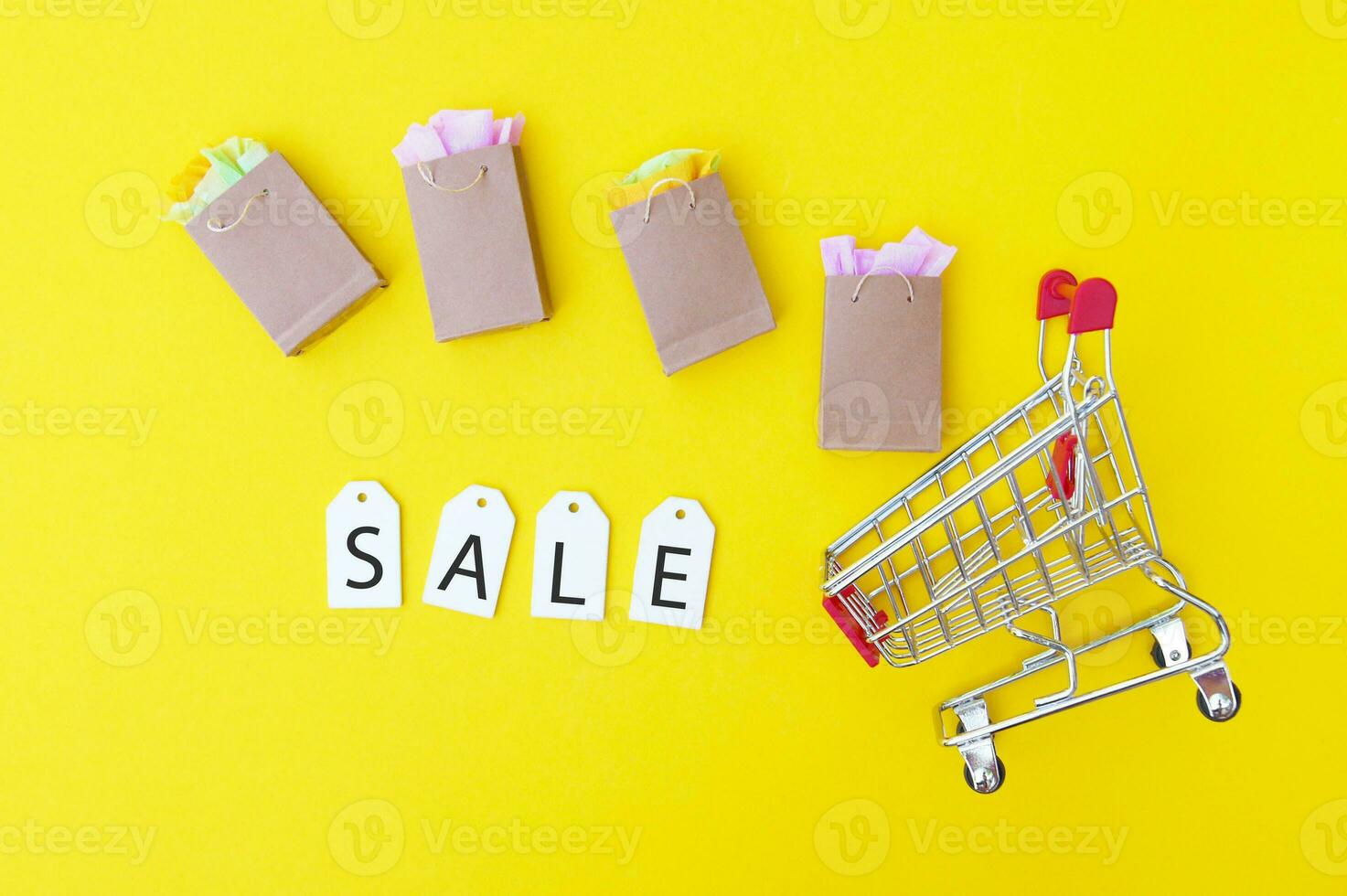 compras carro con papel pantalones y blanco etiquetas con el palabra rebaja en un amarillo antecedentes. foto