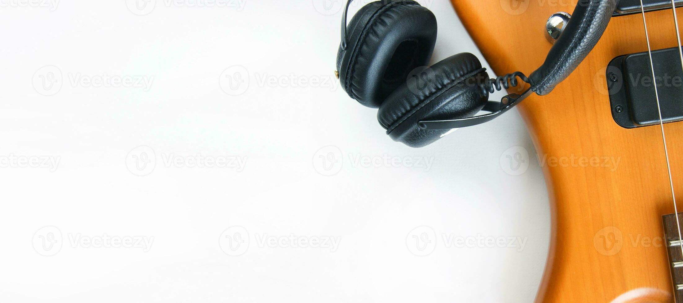 Portable black headphones and bass guitar on white background. photo