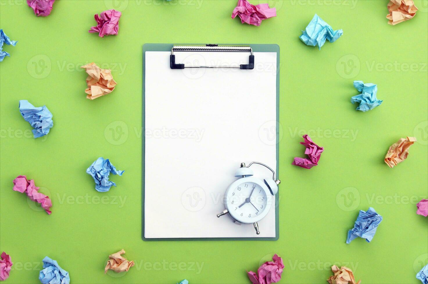 Vintage white alarm clock, clipboard and crumpled colorful stickers around. photo