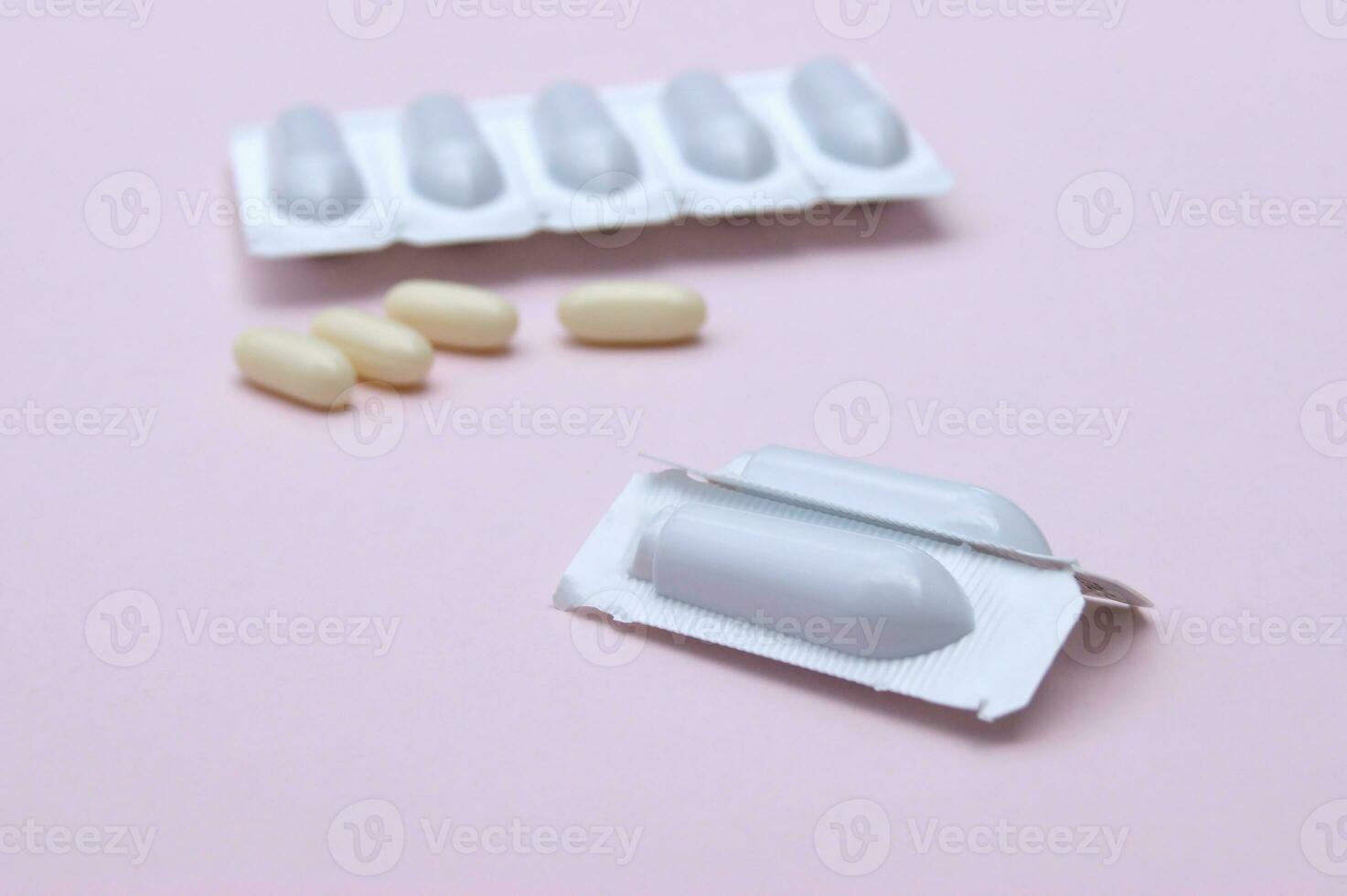 Gynecological medicines for women's health in form of suppository, capsules on pink background. photo