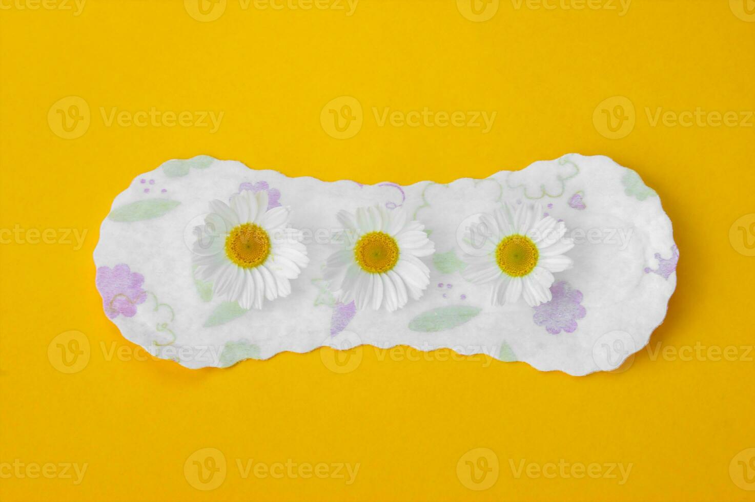 Menstrual pads with chamomiles on yellow background. photo