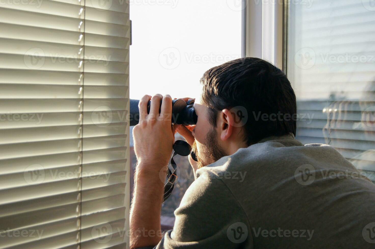 joven hombre en pie mirando con prismáticos foto