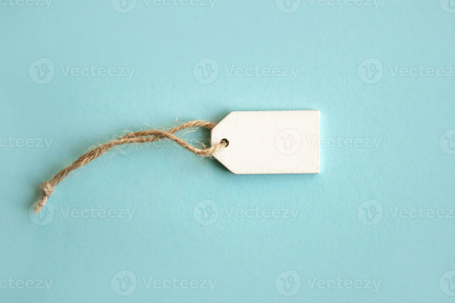 Blank white wooden price tag or label isolated on light blue background. photo