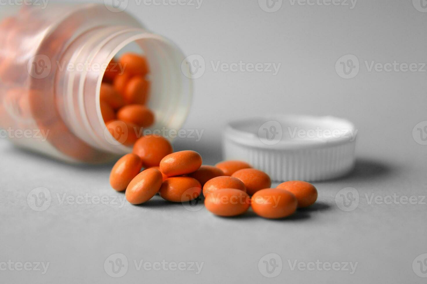 Inverted jar with orange pills on a gray background photo