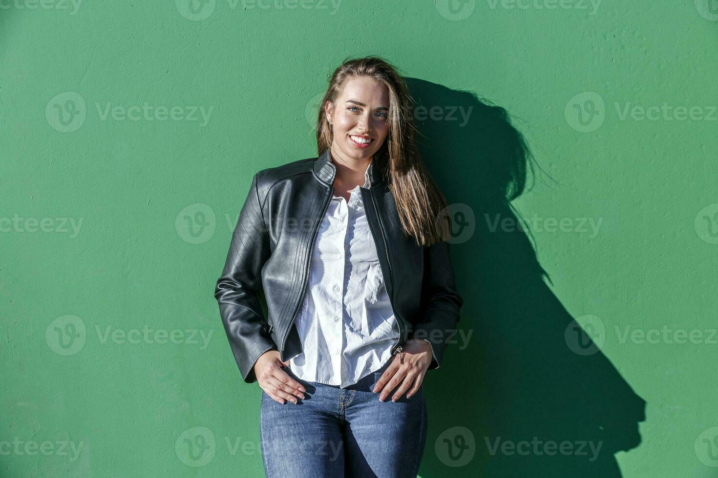 Smiling woman with thumbs in pockets photo