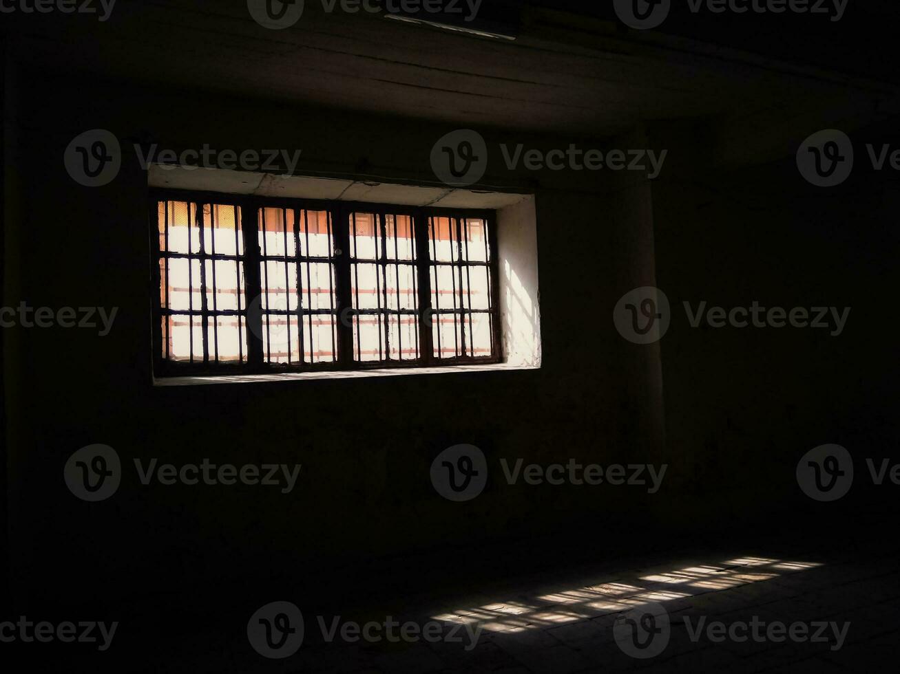 Rectangular window with double frame and shining light leaving a reflection of it on the floor, photography taken from a dark room bottom up view photo