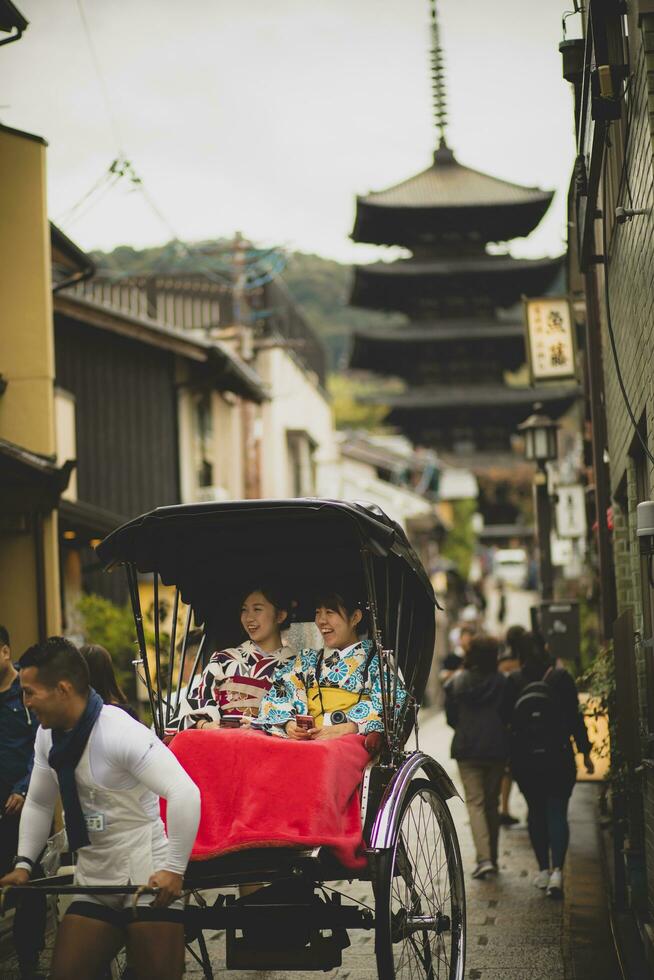 Kioto Japón - noviembre9,2018 japonés mujer vistiendo kimono antiguo traditon ropa sentado en bicitaxi en yasaka calle, yasaka santuario uno de más popular de viaje destino en Kioto foto