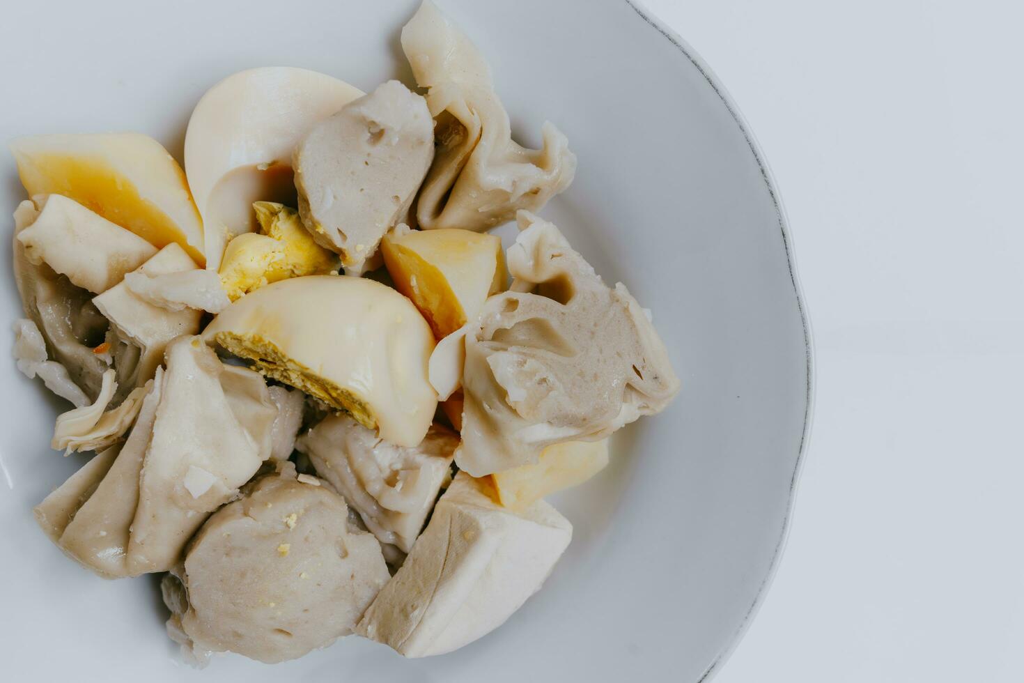 Close up of Siomay Bandung or steamed dumplings, traditional Indonesian street snacks without peanut sauce and soy sauce, served on a white plate. Copy space. Indonesian culinary food concept. photo