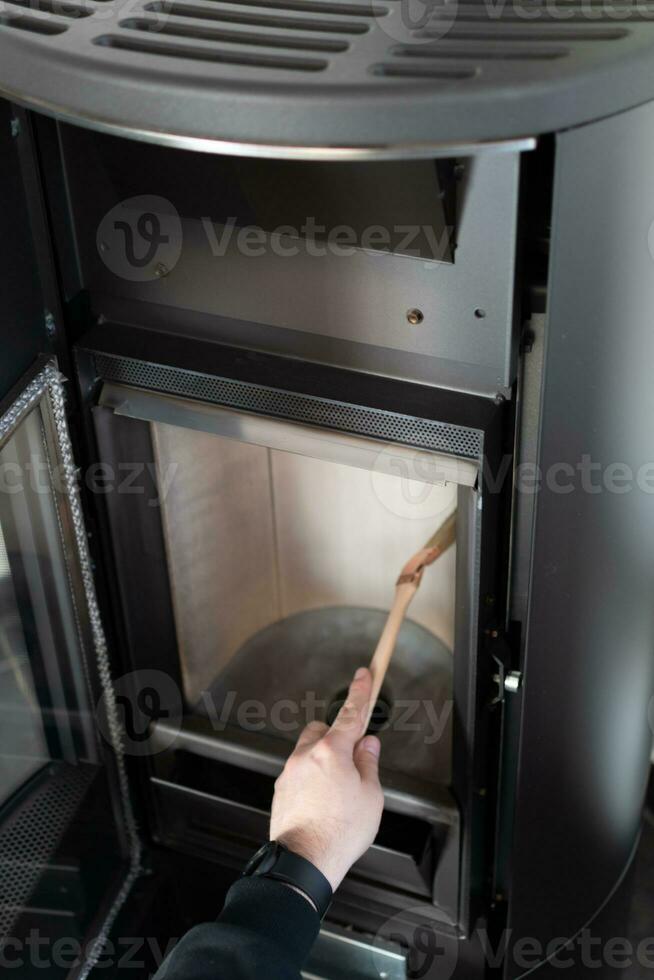 Man cleaning pellet stove with brush photo