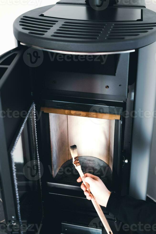 Man cleaning pellet stove with brush photo