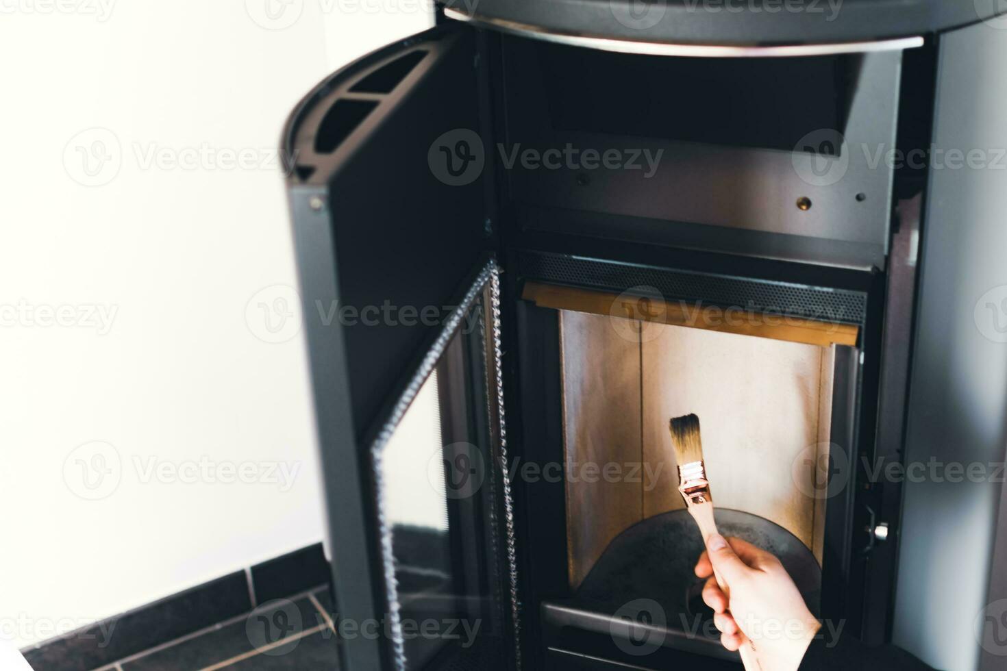 Man cleaning pellet stove with brush photo