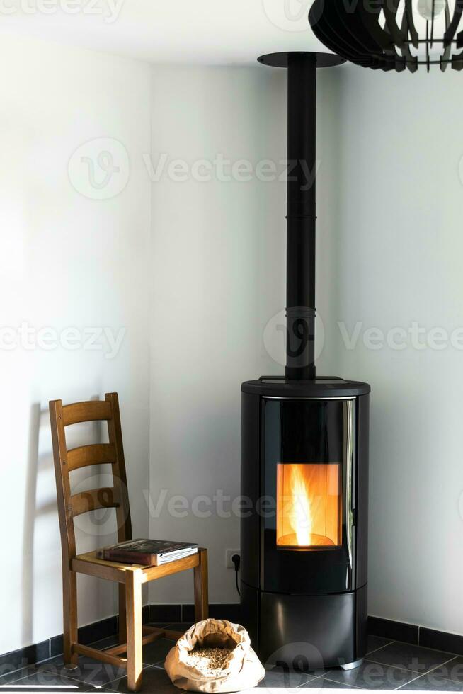 Modern black stove with burning flames and pellet bag in a living room photo