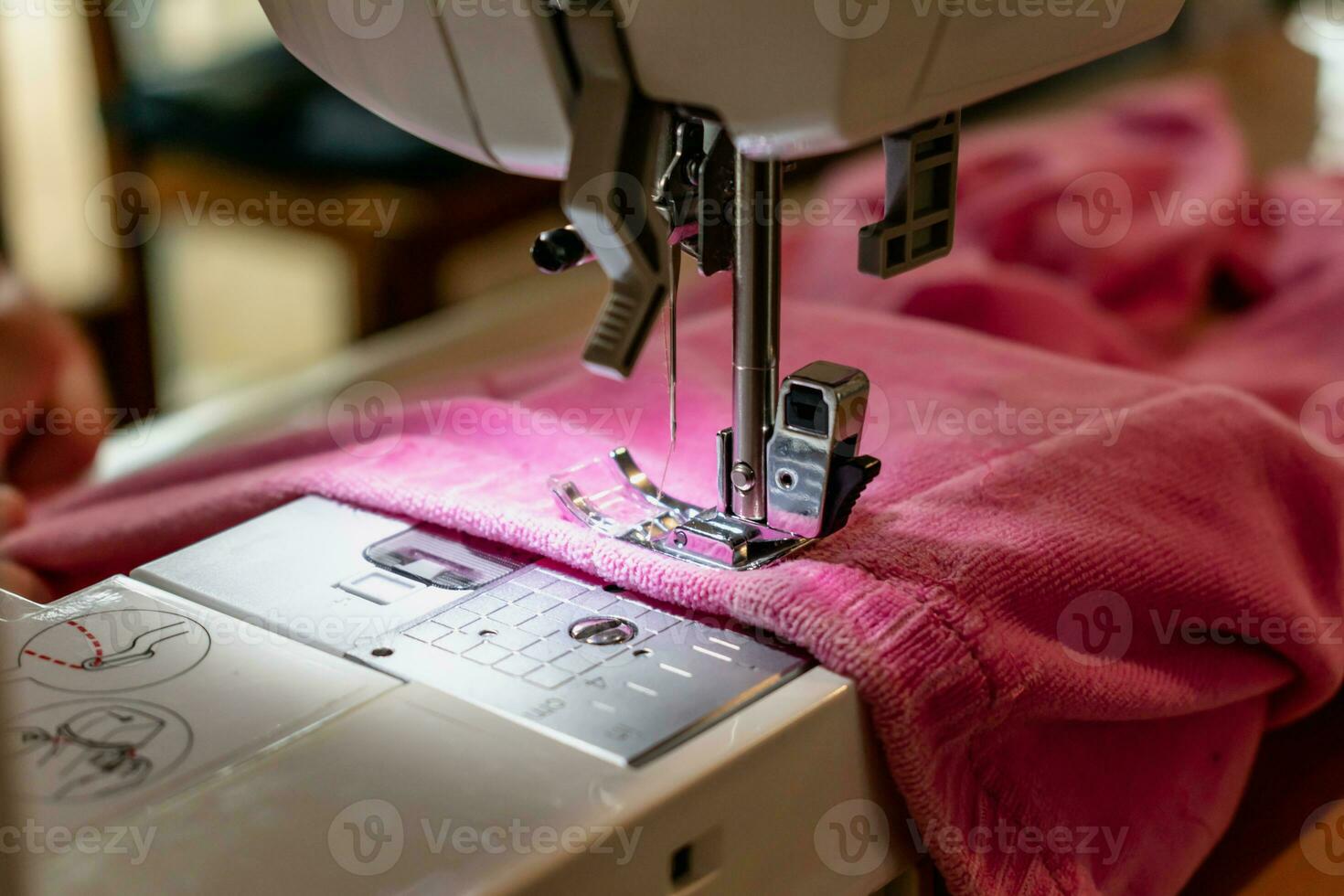 Man using a sewing machine with a pink garment, for repair work, customization, creation, upcycling photo